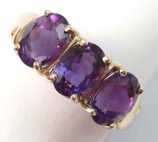 Appraisal: AMETHYST AND TEN KARAT GOLD RING set with three oval-cut