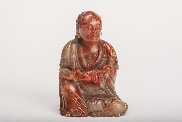 Appraisal: A CHINESE BROWN RED AND GREYISH SOAPSTONE SEATED FIGURE of