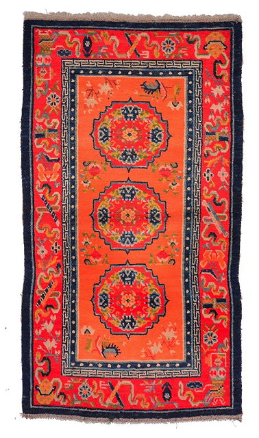 Appraisal: A TIBETAN RED GROUND RUG with three foliate medallions within