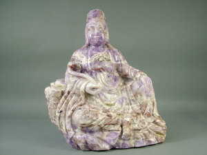 Appraisal: A Chinese variegated liliac hardstone seated figure depicting a deity