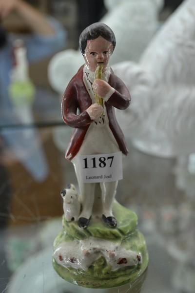 Appraisal: TH CENTURY STAFFORDSHIRE POTTERY FIGURE PLAYING A PENNY WHISTLE