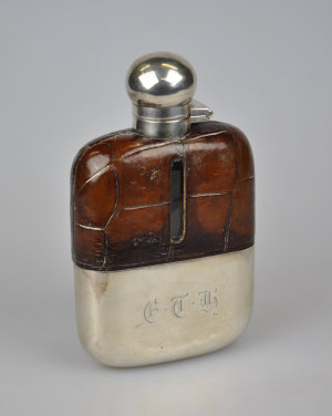 Appraisal: An Edwardian leather-bound hip flask with hinged silver bun cover