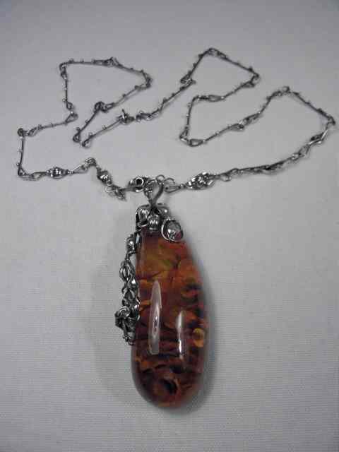 Appraisal: Sterling silver and amber floral pendant Amber has encased flower