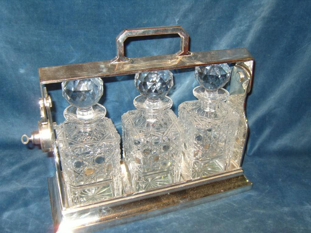 Appraisal: A silver plated -bottle Tantalus containing three cutglass decanters and