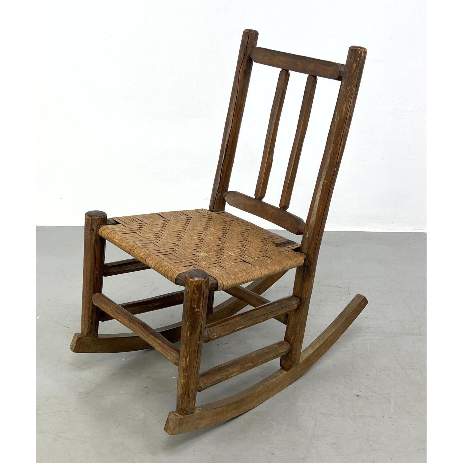 Appraisal: Rustic American country rocker with woven reed seat Dimensions H