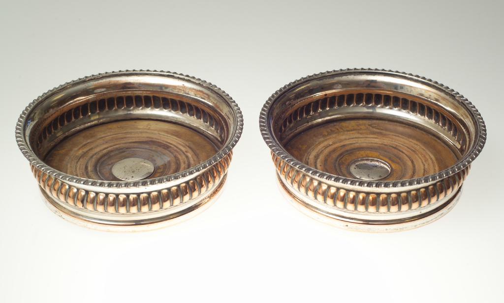 Appraisal: PAIR OF SILVER-PLATED WINE COASTERS IN GEORGIAN STYLE with gadrooned