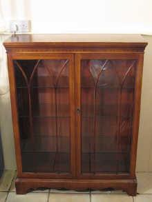 Appraisal: A mahogany display cabinet with glazed lancet doors and three