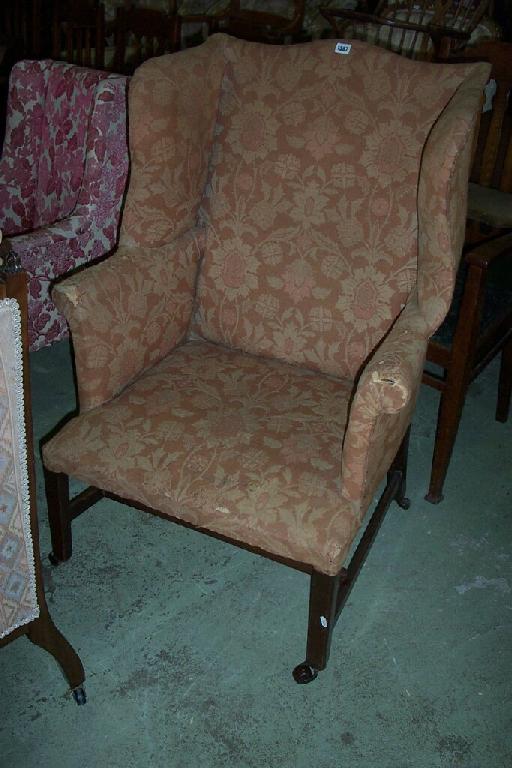 Appraisal: An th century winged chair with scrolled arms and upholstered