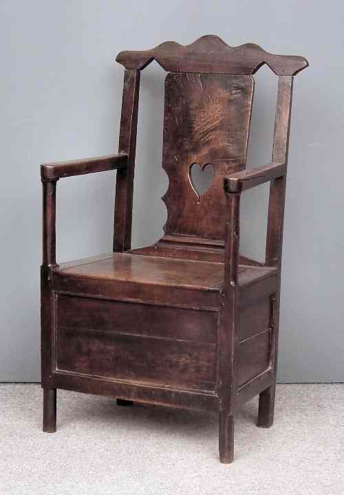 Appraisal: An th Century panelled oak commode armchair with shaped cresting