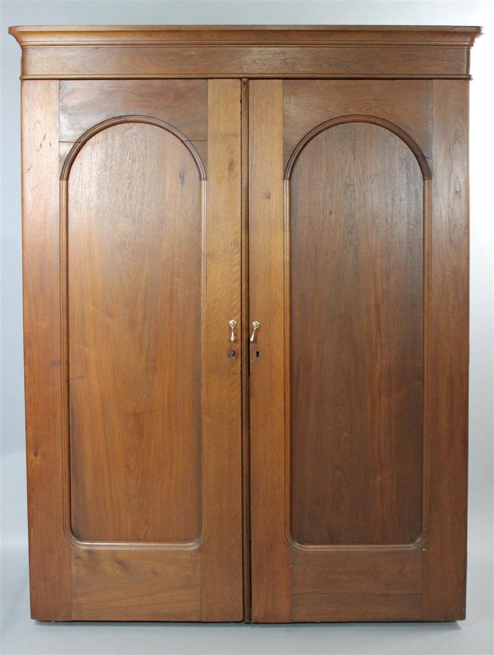 Appraisal: AMERICAN WALNUT WARDROBE having a molded cornice above two arching