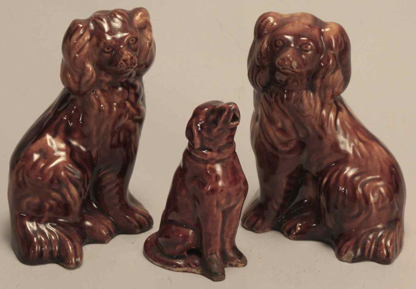 Appraisal: THREE ANTIQUE ROCKINGHAM DOGSEnglish or American th CenturyPair of spaniels