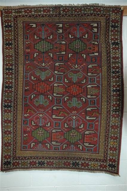 Appraisal: AN OLD CAUCASIAN RED GROUND RUG with continuing stylised pattern