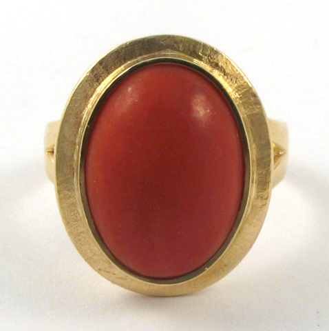 Appraisal: CORAL AND EIGHTEEN KARAT GOLD RING centering oval coral cabochon