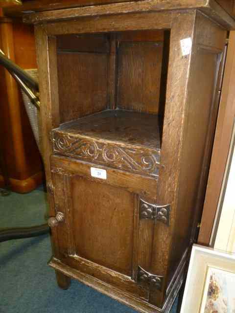 Appraisal: A REPRODUCTION OAK BEDSIDE CUPBOARD with carved panel door across