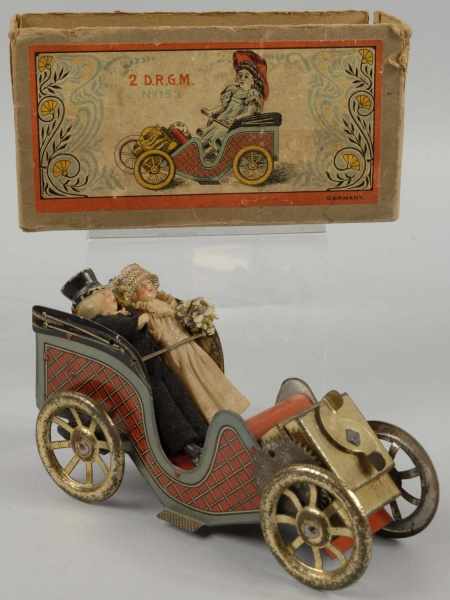 Appraisal: Tin Automobile Wind-Up Toy Description German Working Two bisque figures