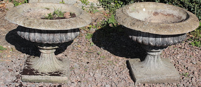 Appraisal: A PAIR OF WEATHERED COMPOSITE STONE CIRCULAR GARDEN URNS of