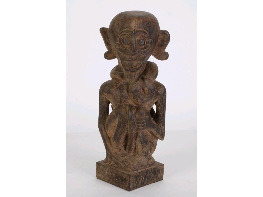 Appraisal: TRIBAL CARVED WOODEN FIGURE in squat pose a lizard upon