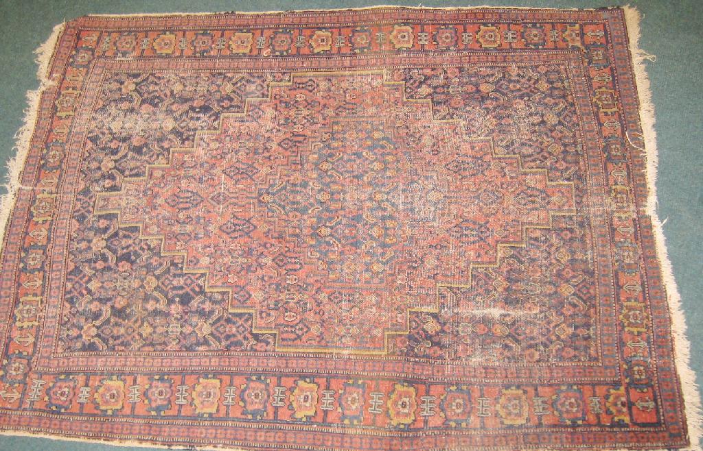 Appraisal: A small bordered Persian Rug with stepped medallion on red