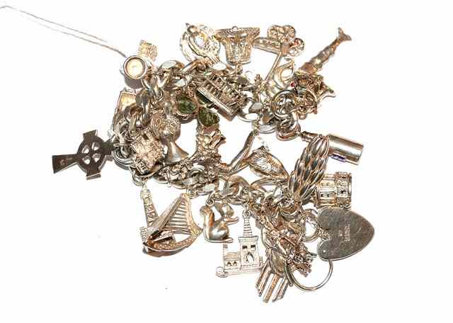 Appraisal: A SILVER CHARM BRACELET with thirty one attached charms and