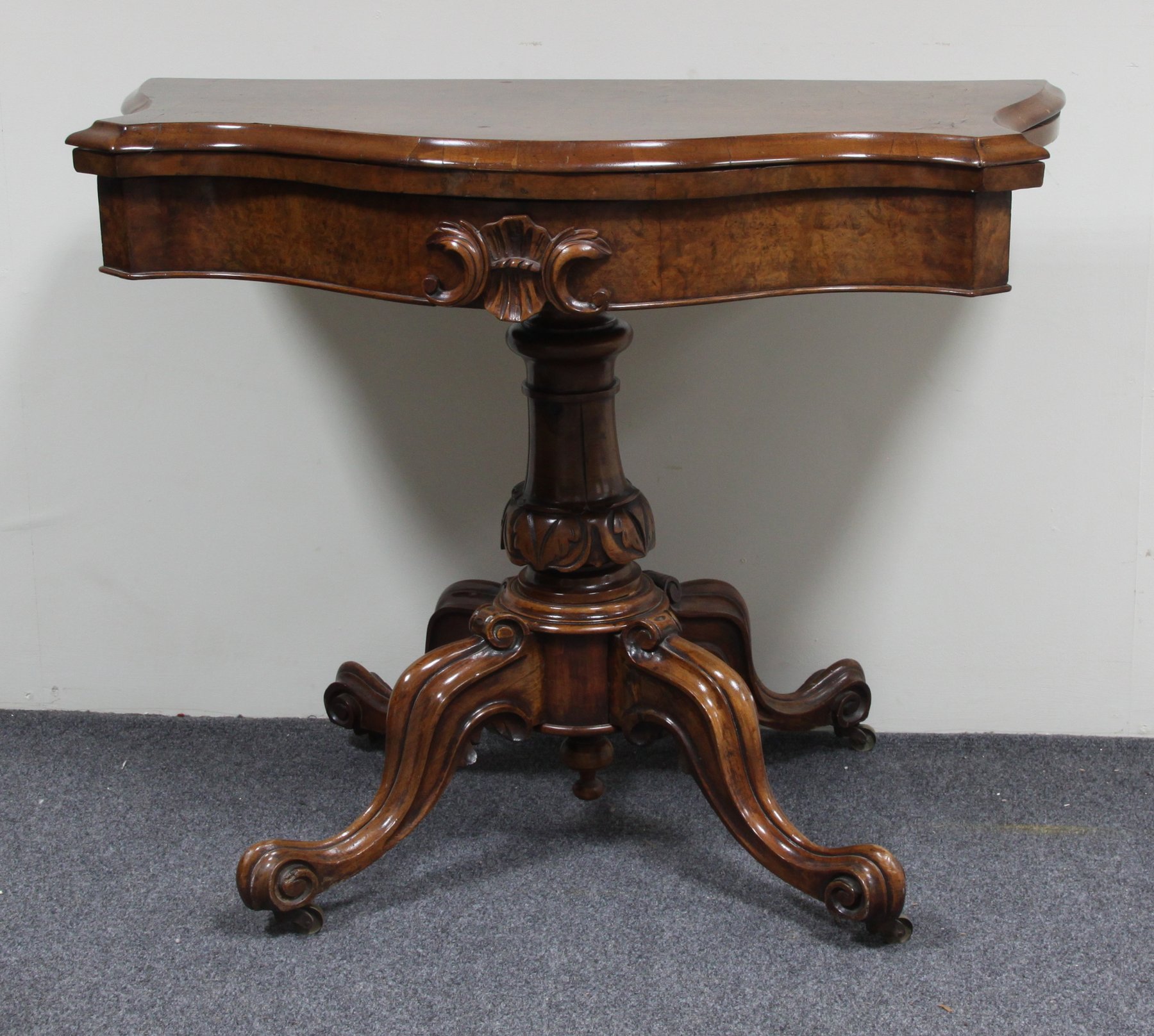 Appraisal: A Victorian walnut card table the fold-over top of serpentine