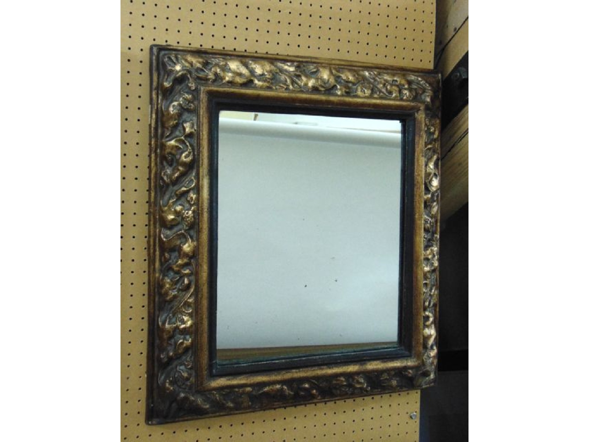 Appraisal: A rectangular wall mirror in an embossed and gilded cushion