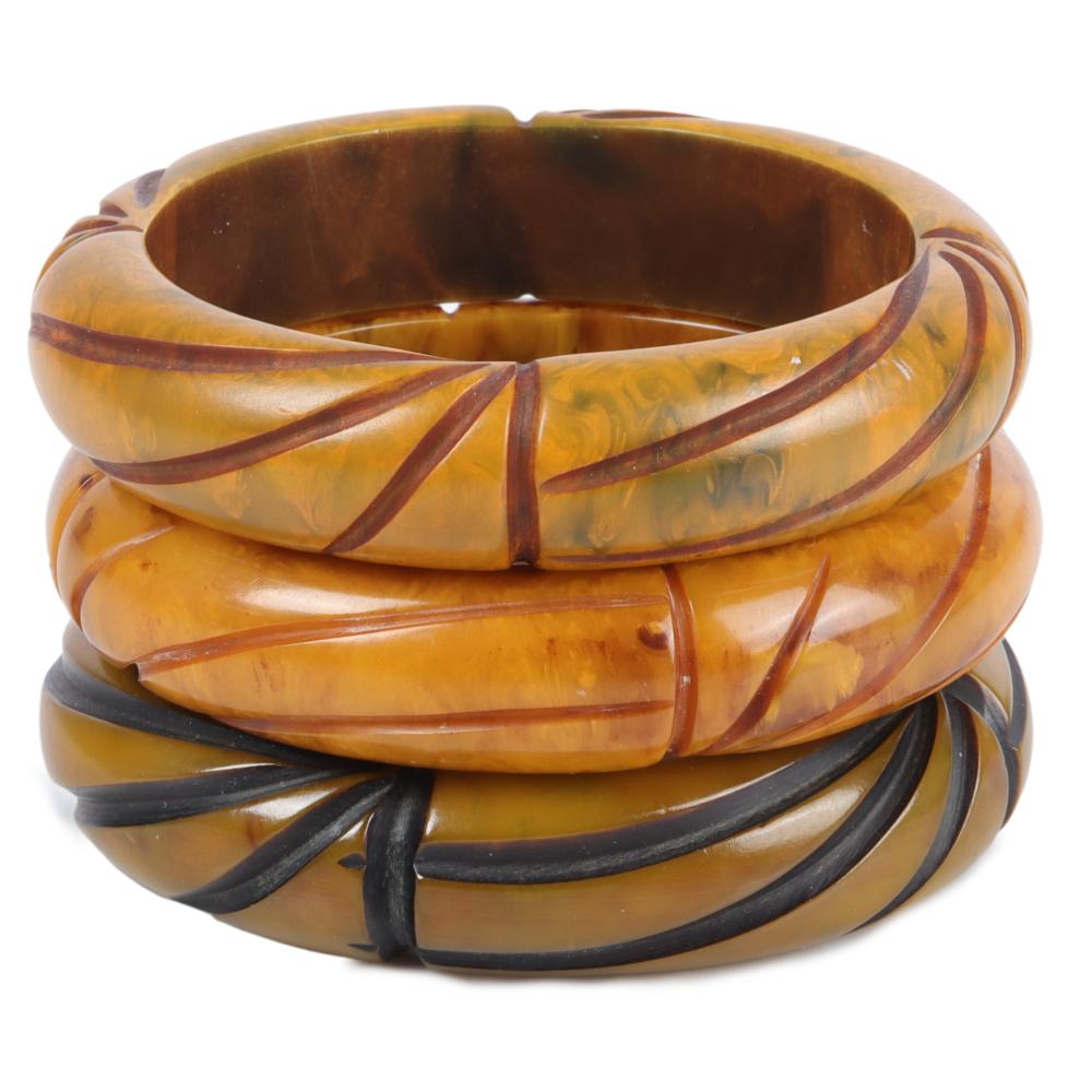 Appraisal: THREE CARVED AND OVER DYED BAKELITE BANGLE BRACELETS W X