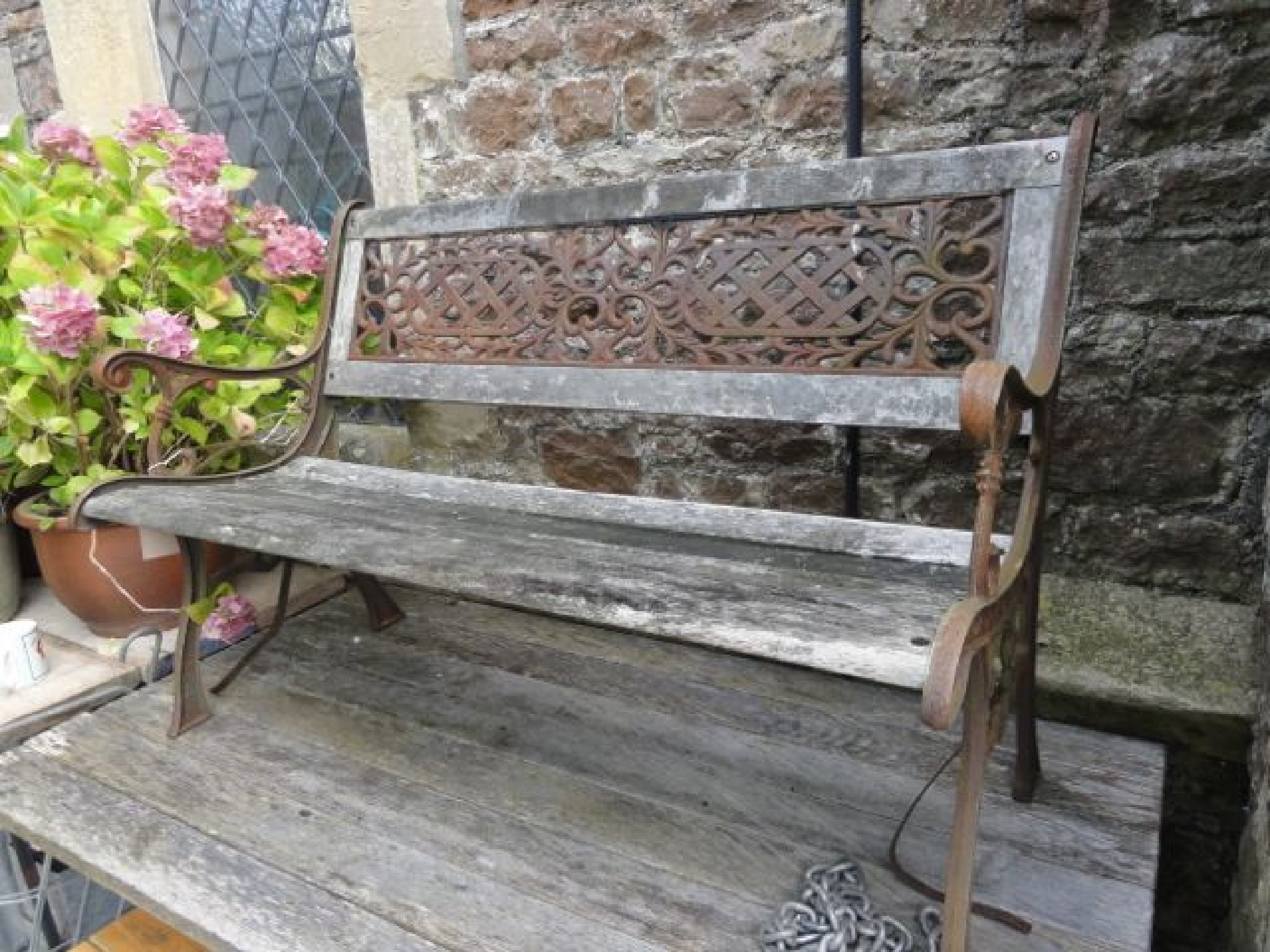 Appraisal: A two seat garden bench with weathered timber seat and