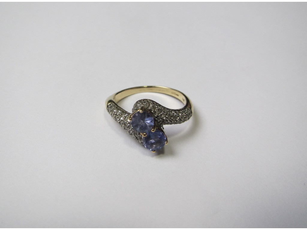 Appraisal: Nine carat gold tanzanite and diamond cross over ring