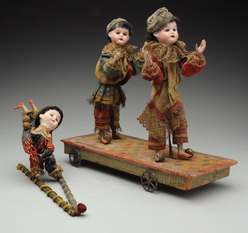 Appraisal: Mechanical Pull Acrobat Toy Three bisque-head acrobats on a wheeled