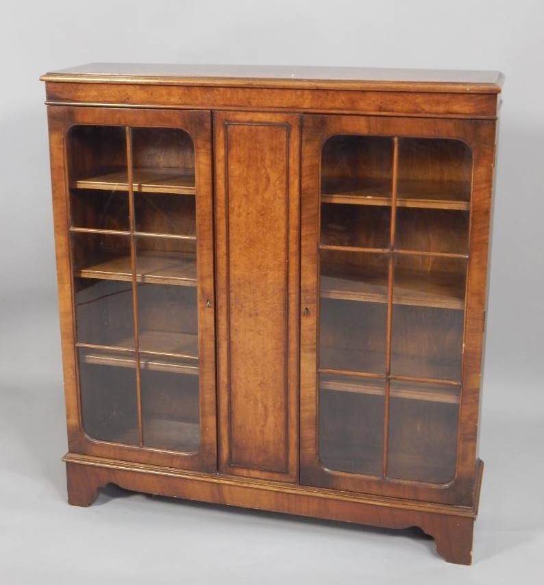 Appraisal: A walnut bookcase with two glazed doors on bracket feet