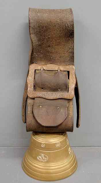 Appraisal: Massive brass cowbell th c with a leather strap and