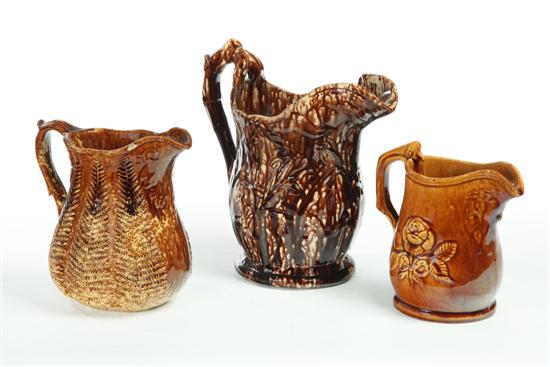 Appraisal: THREE ROCKINGHAM PITCHERS Tall dark brown mottled glazed pitcher with