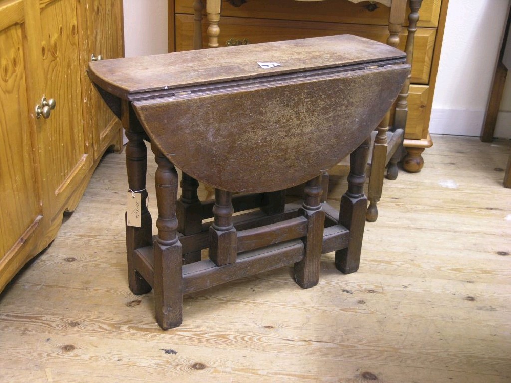 Appraisal: A dark oak gateleg dining table on baluster turned underframe