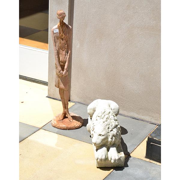 Appraisal: AN EARTHENWARE FIGURE OF A WOMAN AND CONCRETE LION FIGURE