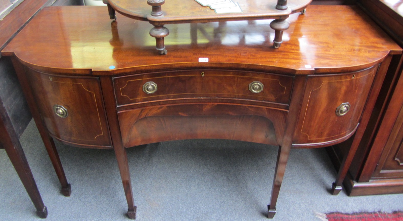 Appraisal: A George III style concave fronted mahogany sideboard on tapering