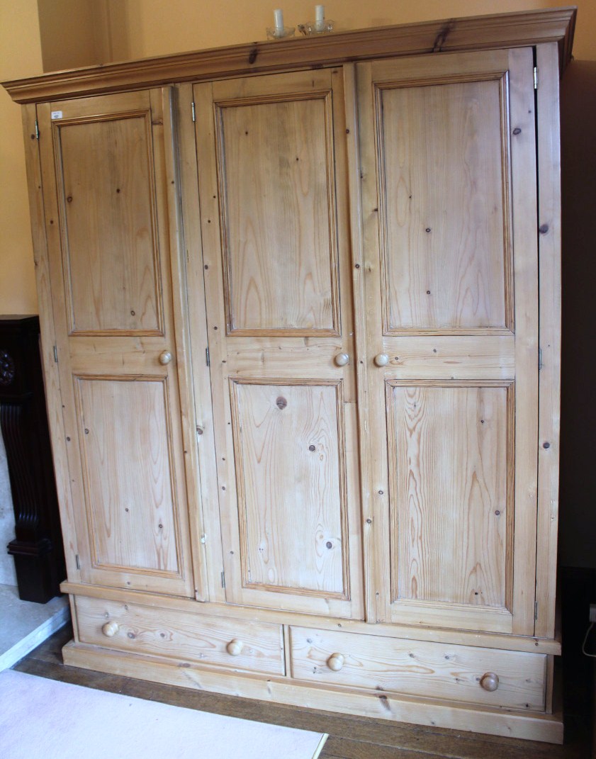 Appraisal: A pine triple wardrobe with moulded cornice and two drawer