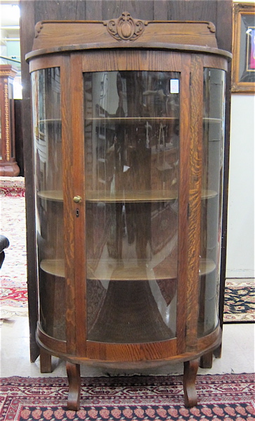 Appraisal: AN OAK AND CURVED GLASS CHINA CABINET American c with