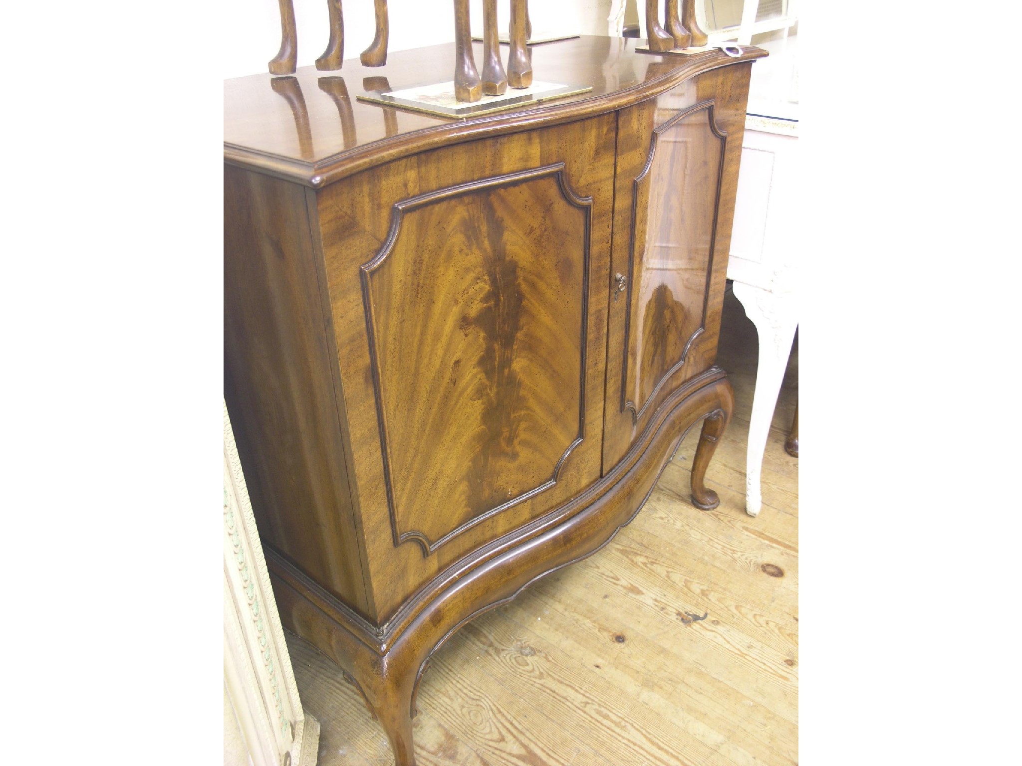 Appraisal: A serpentine-fronted mahogany cupboard enclosed by a pair of panelled