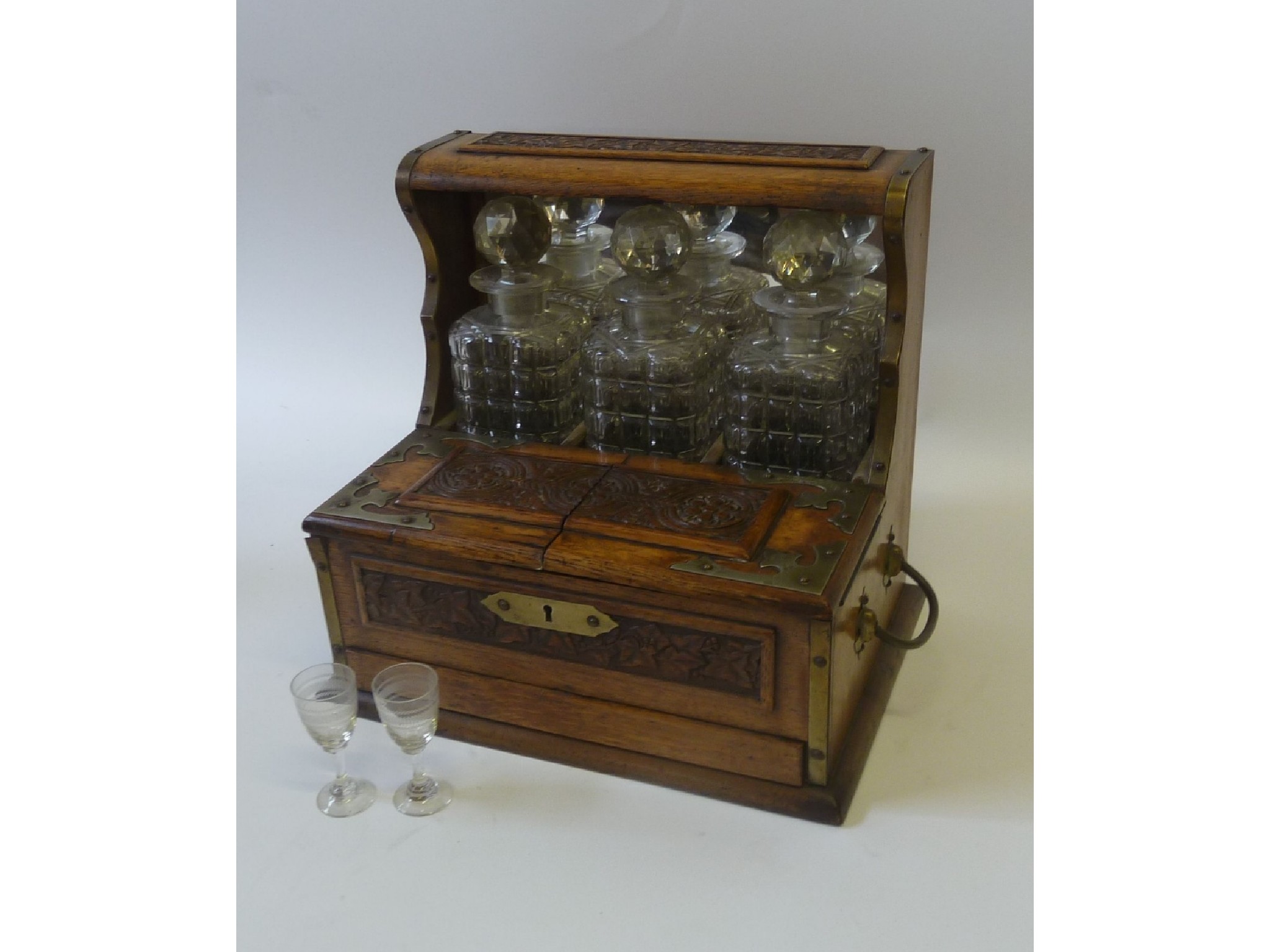 Appraisal: LATE VICTORIAN CARVED OAK THREE BOTTLE TANTALUS with mirror glazed