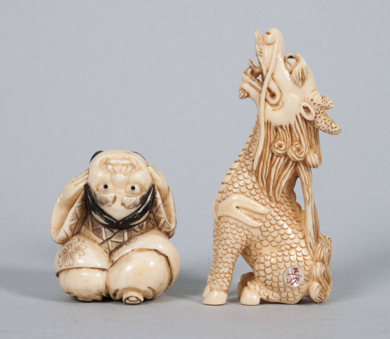 Appraisal: Two Japanese carved ivory netsukes Dragon and child with demon