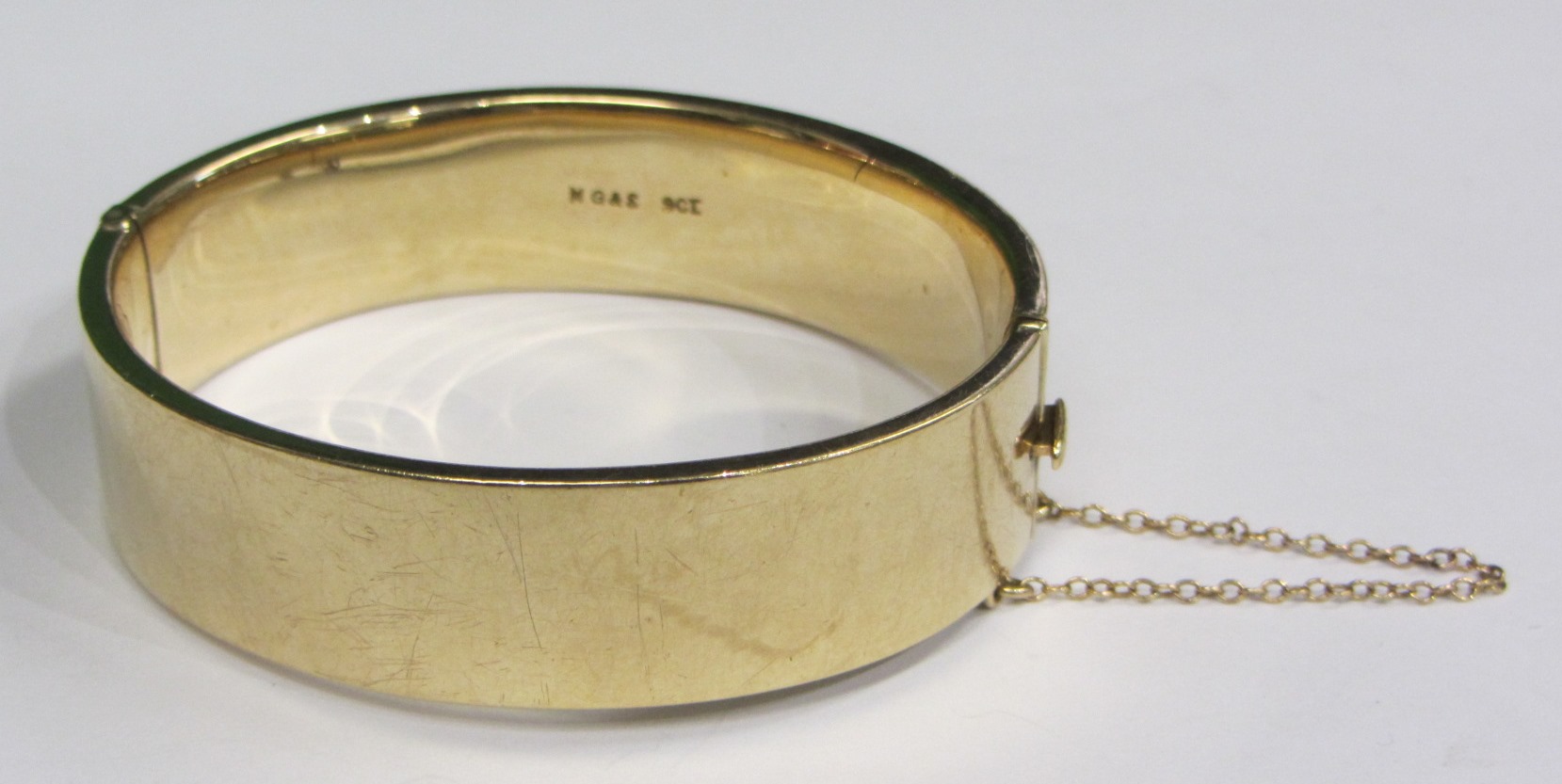 Appraisal: A gold oval hinged bangle the front with engine turned