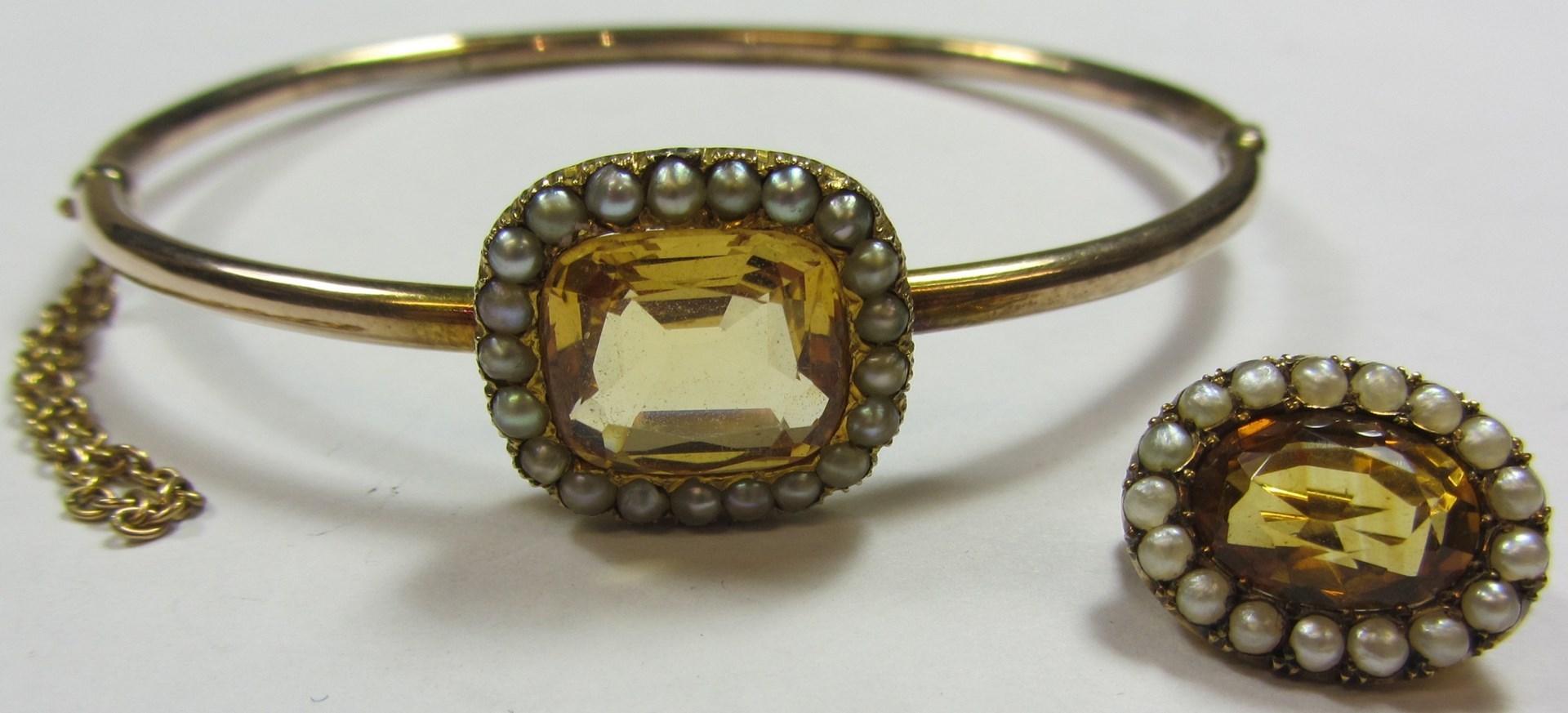 Appraisal: A gold topaz and half pearl set oval hinged bangle