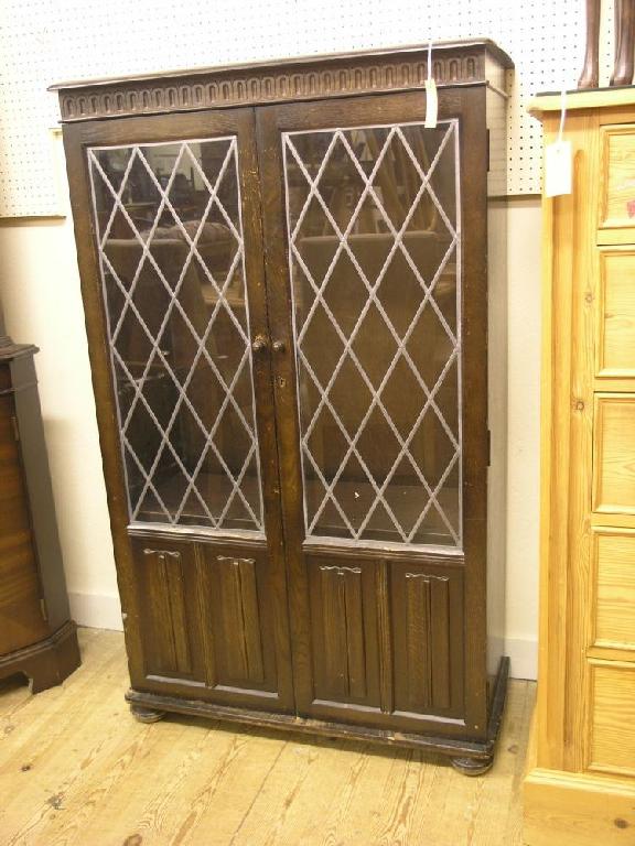 Appraisal: A dark oak display cabinet enclosed by a pair of