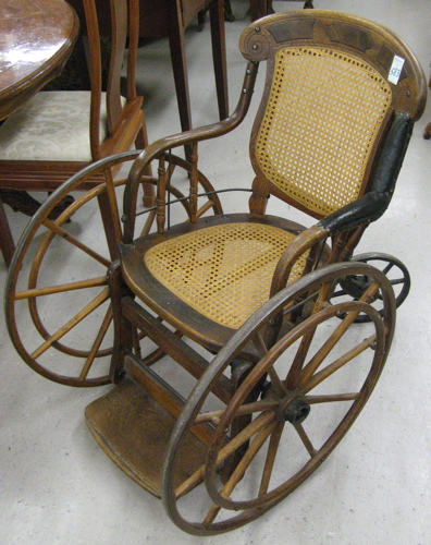 Appraisal: ANTIQUE OAK WHEEL CHAIR American late th century The three-wheel