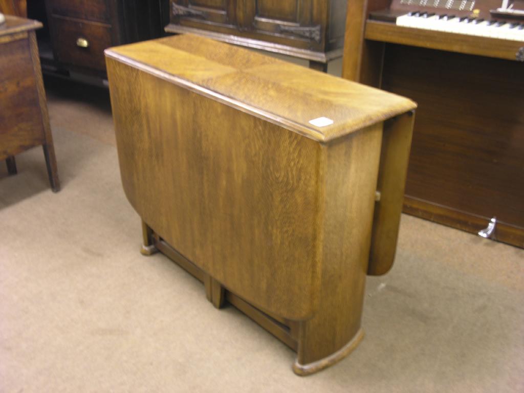 Appraisal: An oak veneered drop leaf dining table on end supports