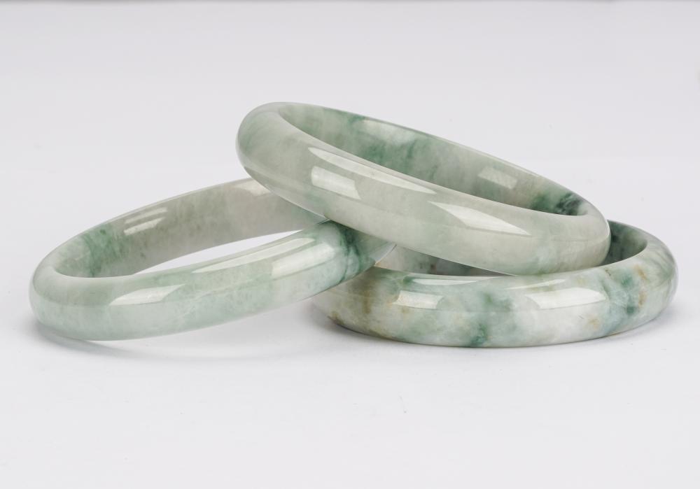 Appraisal: THREE JADE BANGLESCondition with iron oxide staining and dark green