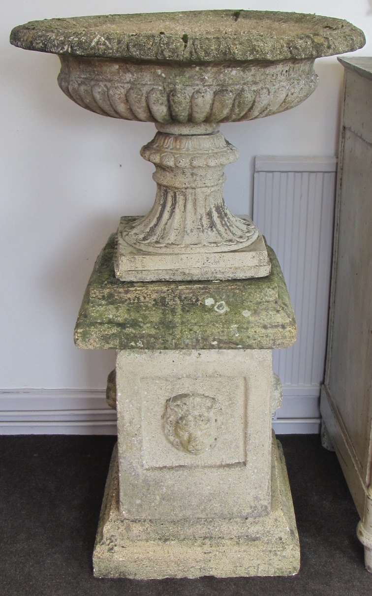 Appraisal: A pair of reconstituted stone shallow fluted urns on stepped