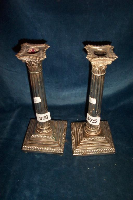 Appraisal: A pair of Corinthian column silver candlesticks with stepped platform