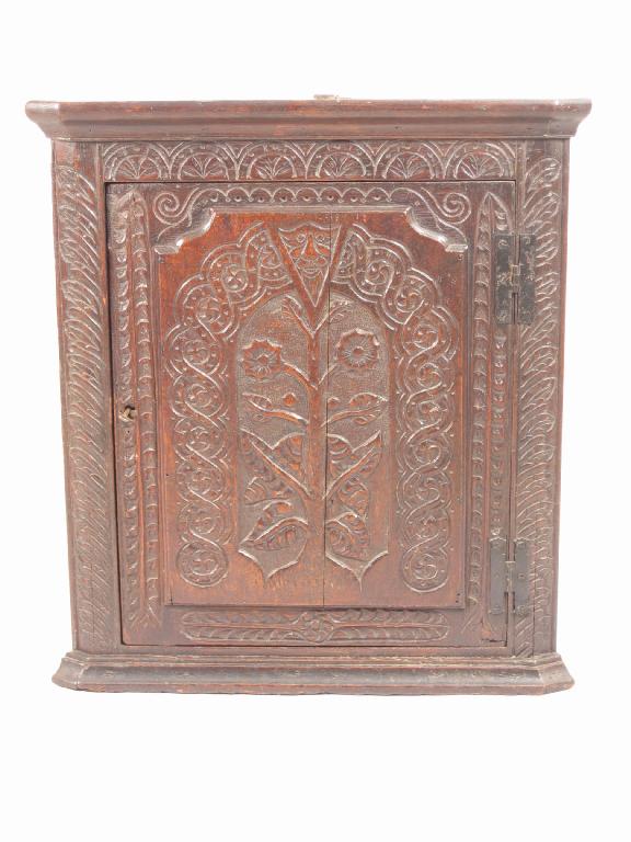 Appraisal: An antique oak hanging Corner Cupboard the door panel carved