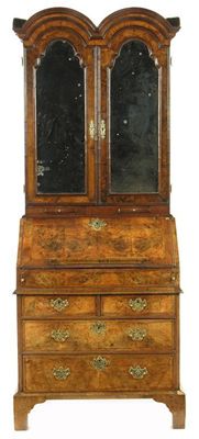 Appraisal: A walnut double domed bureau cabinet the moulded cornice above